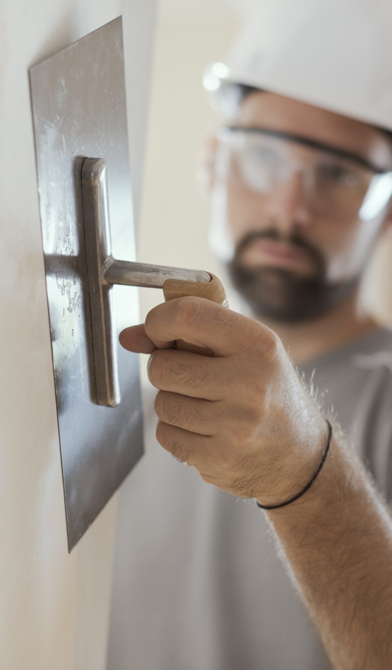 Professional craftsman applying plaster with a trowel, home renovation concept